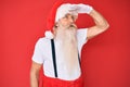 Old senior man with grey hair and long beard wearing white t-shirt and santa claus costume very happy and smiling looking far away Royalty Free Stock Photo