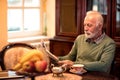 Old senior man sitting at home alone and reading a newspaper Royalty Free Stock Photo