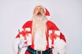 Old senior man wearing santa claus costume holding presents angry and mad screaming frustrated and furious, shouting with anger Royalty Free Stock Photo