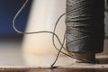 Old sewing machine needle with black thread, on a old grungy work table. Tailor`s work table. textile or fine cloth making. indust Royalty Free Stock Photo