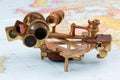 old brass sextant lying on world map