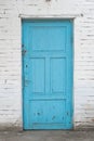 Old shabby blue wooden door on a white brick wall Royalty Free Stock Photo