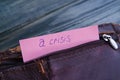 Old shabby empty leather wallet with word Crisis written on pape