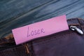 Old shabby empty leather wallet with word Loser written on paper