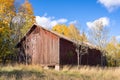 Old shabby red barn in the fall season. Vintage photo. An abandoned farm in a rural location and wooden warehouse for storage of Royalty Free Stock Photo