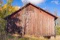 Old shabby red barn in the fall season. Vintage photo. An abandoned farm in a rural location and wooden warehouse for storage of Royalty Free Stock Photo