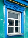 Old shabby retro vintage window with blue painted trim on green