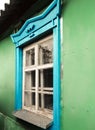 Old shabby retro vintage window with blue painted trim on green