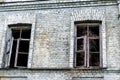 Old shabby ruined abandoned brick building wall facade with two wooden brocken glass windows and dark black background Royalty Free Stock Photo