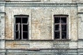 Old shabby ruined abandoned brick building wall facade with two wooden brocken glass windows and dark black background. Shattered Royalty Free Stock Photo