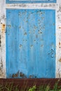 Old shabby wooden door, blue and white, with rusty hinges, a handle, a lock, and nails. Copy space. Royalty Free Stock Photo