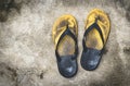 Old and shabby yellow flip-flops lay on the concrete floor Royalty Free Stock Photo