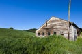 Old shed by grassy hill.