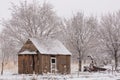 An old shed a piece of antique farm machinery and the trees around them are covered by a thin layer of snow on a cold winter day Royalty Free Stock Photo