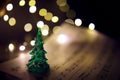 Old sheet with Christmas music notes as background against blurred lights. Christmas music concept Royalty Free Stock Photo