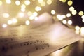 Old sheet with Christmas music notes as background against blurred lights Royalty Free Stock Photo