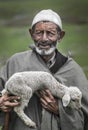 Old shepherd holding a baby goat