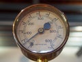 Old shiny brass round pressure gauge with a round dial marked in numbers and a black metal needle