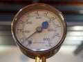 Old shiny brass round pressure gauge with a round dial marked in numbers and a black metal needle