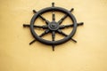 Old ship wheel mounted on a yellow wall as design and decoration element. Copy space Royalty Free Stock Photo