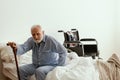 Old sick man with grey beard and hair wearing blue pajamas and sitting on bed at home Royalty Free Stock Photo