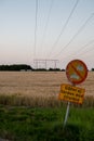 An old sign informing drivers that they are not allowed to enter the rural road next to an agricultural field with power lines in