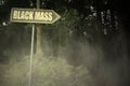 Old signboard with text black mass near the sinister forest