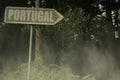 old signboard with text portugal near the green sinister forest