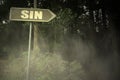 Old signboard with text sin near the sinister forest Royalty Free Stock Photo