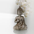 Old silver color statuette Buddha sitting in meditation pose on light blurred orchid flower background