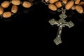 Old silver crucifix with wooden rosary bead on black background