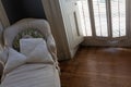 Old slipcovered daybed beside a shuttered window, antique wood floors, copy space
