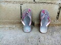 Old slippers on dirty ground and part of brick . Pair of shoes on background.