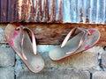 Old slippers hung with nails that were nailed to wood and had a rusted zinc. and bricks background. Royalty Free Stock Photo