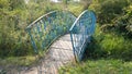 Old small blue bridge over the river. A trip to the countryside. Bent metal Royalty Free Stock Photo