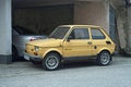 Old small cheap yellow compact oldtimer car Polski Fiat 126p parked