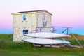 Old small cottage with peeling yellow paint with two canoes Royalty Free Stock Photo