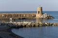 Old small lighthouse and stone wave breakers of Recco on a sunny summer day.