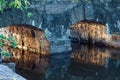 Old, small stone bridge close-up across small river, warm sunlight reflected from arches bridge, calm water surface Royalty Free Stock Photo