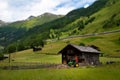 Old small wooden house and green tractor in the alps Royalty Free Stock Photo