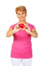 Old smiling woman holding red toy heart