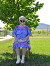 Old smiling woman in sungalsses  sitting on a chair Royalty Free Stock Photo