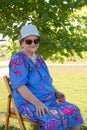 Old smiling woman in sungalsses  sitting on a chair Royalty Free Stock Photo