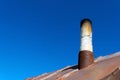 Old smoke pipe out of the rusty iron roof. Royalty Free Stock Photo