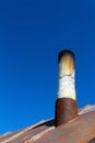 Old smoke pipe out of the rusty iron roof. Royalty Free Stock Photo