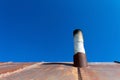 Old smoke pipe out of the rusty iron roof. Royalty Free Stock Photo