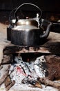 Old smoked metal pot on wooden fireplace while cooking indian tea. Outdoor kitchen.