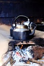 Old smoked metal pot on wooden fireplace while cooking indian tea. Outdoor kitchen.