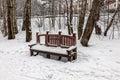 Old snow-covered wooden bench in the winter forest Royalty Free Stock Photo
