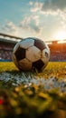 Old soccer ball on grass with the glow of sunset, empty stadium in background Royalty Free Stock Photo